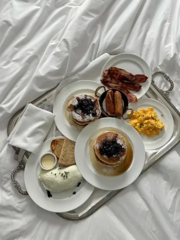 Pancake, scrambled egg, bacon, cream cheese, sausages and bread