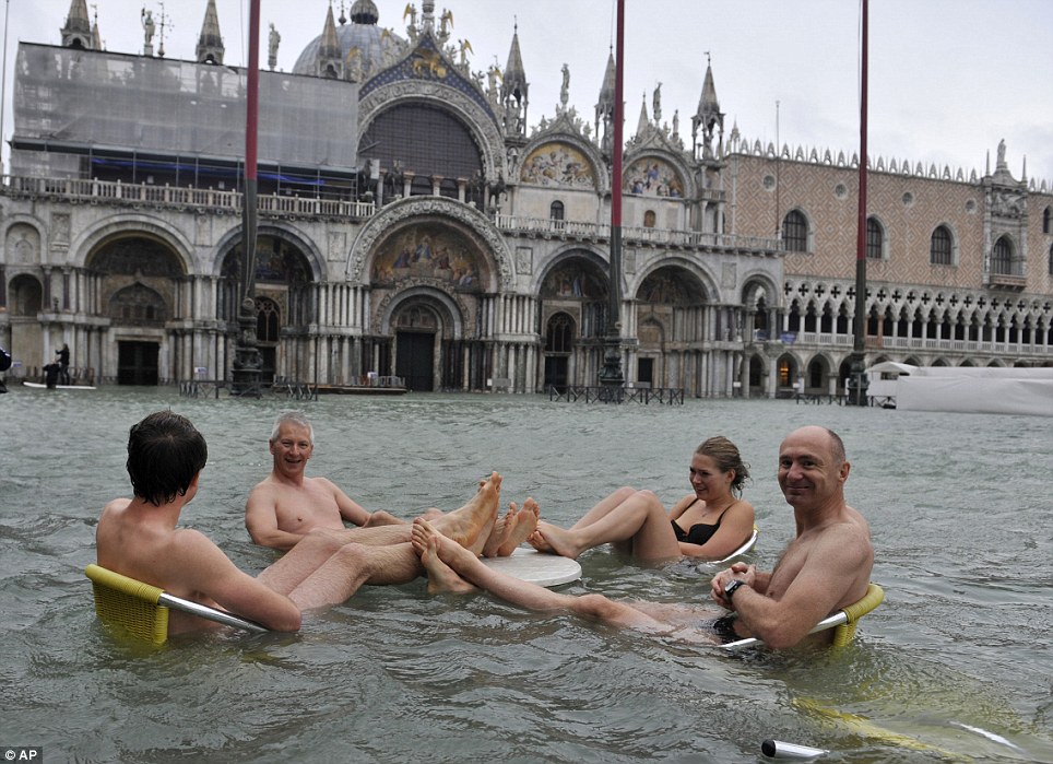 People sit at the table of a bar in a flooded St. Mark′s Square today after high tides 
have flooded the romantic city in Italy