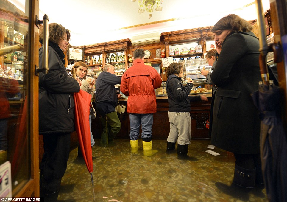 People take a coffee break in a flooded shop as rainfall reached 59inches in Venice