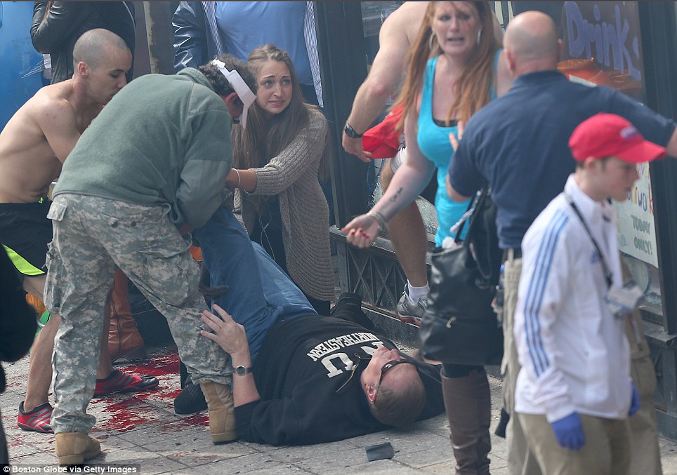คนที่เดินผ่านช่วยคนบาดเจ็บบนทางเท้าใกล้มาราธอนกีฬาหลังจากสองระเบิดเกือบจะพร้อมกันออกไปใกล้เส้นชัยของ 117th บอสตันมาราธอนวันนี้