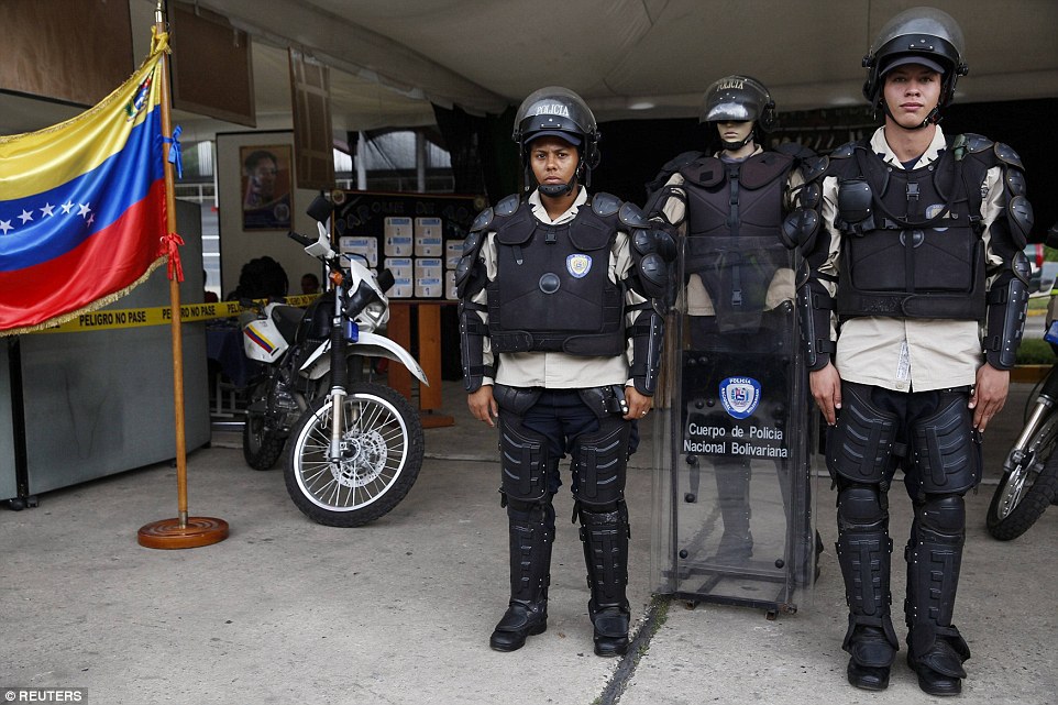 Venezuelan national police officers pose for a picture with their riot equipment in Caracas. They stand next to a mannequin dressed in uniform