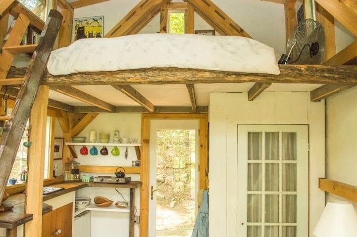 The loft bedroom with built-in shelving is above the kitchen, reachable from the ladder. 