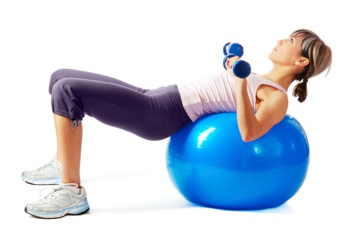 Young beautiful sportswoman exercising on a fitness ball.