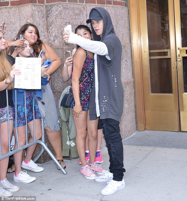 Comfy casual: The 21-year-old singer was dressed casually and comfortable in a long sleeve white shirt and tattered jacket with the hood over his head and sports cap