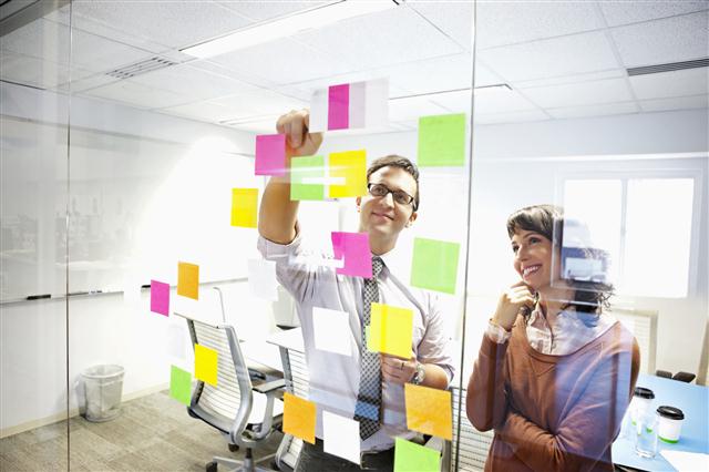 Man-and-women-sticking-post-it-notes-to-glass